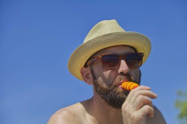 Sakallı ve kulübesi olan genç adam yaz tatillerinde çubuğun üzerinde buzun keyfini çıkarıyor.