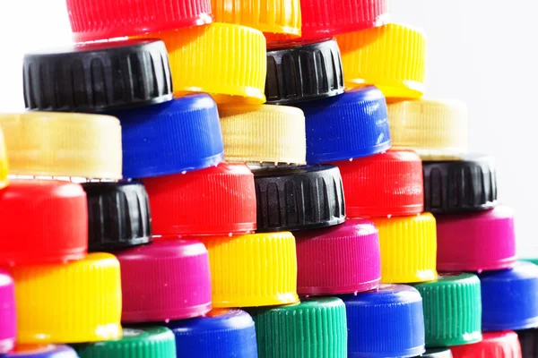 Many plastic multicolored bottle caps on white background.