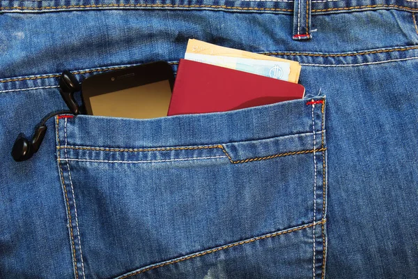 Passport and money with modern smartphone in the back pocket of jeans.