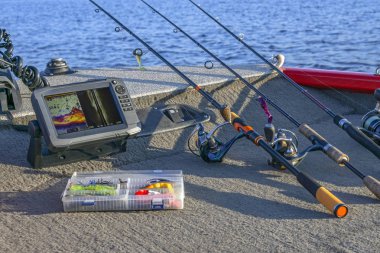 Fishing tackle set and fishfinder, echolot, sonar at the boat. Spinning rods with reels and lures clipart
