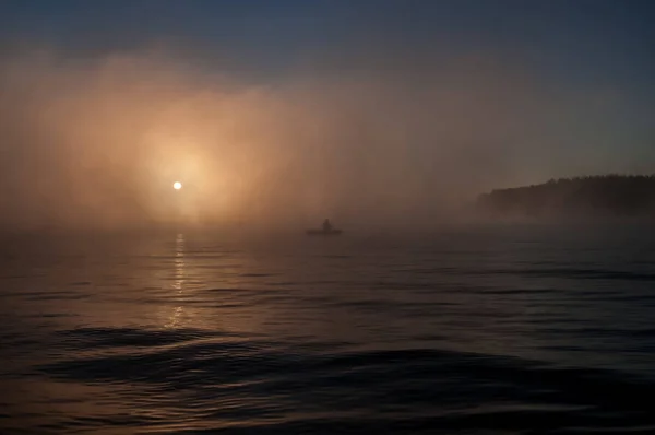 Boat with fishermen at lake in fog. Fishing background