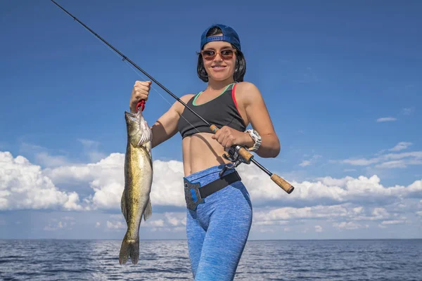 Happy fisher woman with zander fish trophy at the boat