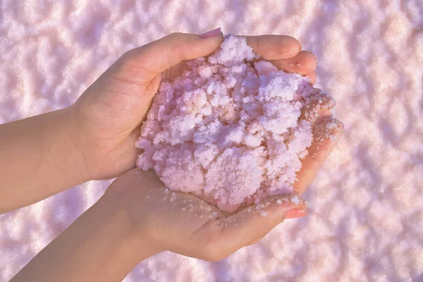 Pink salt in hands from Sivash lake. Spa, medicine dermatology background.