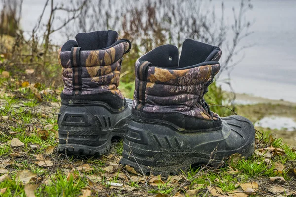 A pair of worn hiking boots on natural background. Dirty boots for hiking, fishing, traveling.