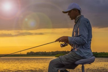 Balıkçı tekne, silüeti. Olta bulutlu gün batımı arka plan üzerinde olan adam