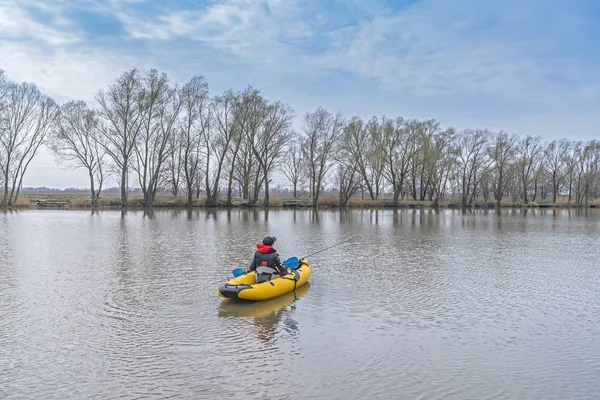 Kayak fishing at lake. Fisherwoman on inflateble boat with fishi