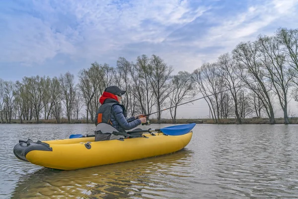 Kayak fishing at lake. Fisherwoman on inflateble boat with fishi