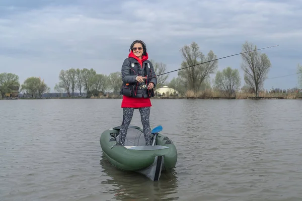 Kayak fishing at lake. Fisherwoman on inflateble boat with fishi