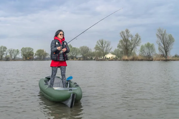 湖でのカヤック釣り.魚と膨らんだボートの漁師の女性 — ストック写真