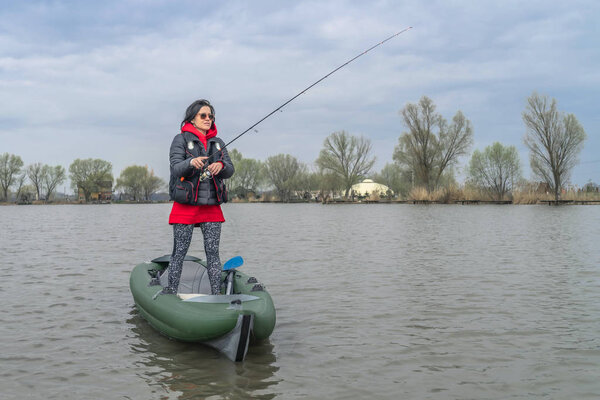 Kayak fishing at lake. Fisherwoman on inflateble boat with fishi