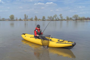Gölde kayak balıkçılığı. Balıkçı kadın balıkçı takım ile şişme tekne de pike balık ile.