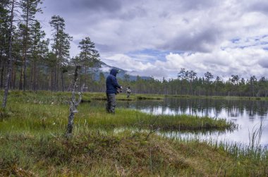Ormanda gölde balık tutmakta yalnız bir balıkçı. Norveç