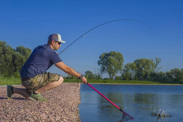 Zona de pesca de truchas. Pescador con caña giratoria en acción jugando a los peces . —  Fotos de Stock