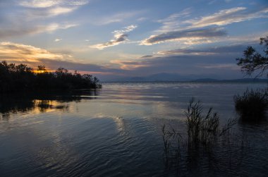 Göl günbatımı. Gökyüzü bulutlar ve ışınları ile