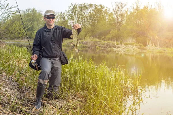 Rybaření. Šťastný rybář, který drží na řece pištiku a rybářskou tyčinku — Stock fotografie