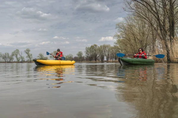 Kayak fishing at lake. Two fisherwomen on inflatable boats with fishing tackle.