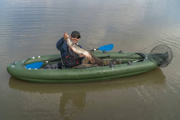 Pesca en kayak. Pescador pescado de lucio capturado en barco inflable con aparejos de pesca en el lago . — Foto de Stock