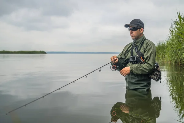 A pescar. Pescador em ação, homem captura peixe por haste giratória — Fotografia de Stock