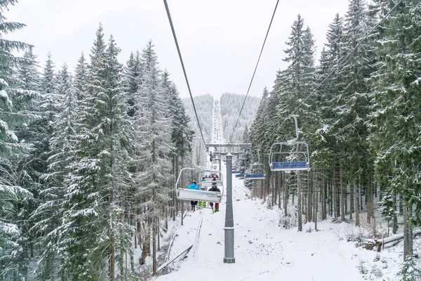 Ukraine, bukovel - 2018 년 12 월 15 일. 많은 스노 보더와 스키를 타는 사람들 이 스노보드를 타고 엘레 베 이터를 타고 스노우 힐로 갑니다. 겨울에 카르파티아 산맥에서 스키를 타는 모습 — 스톡 사진