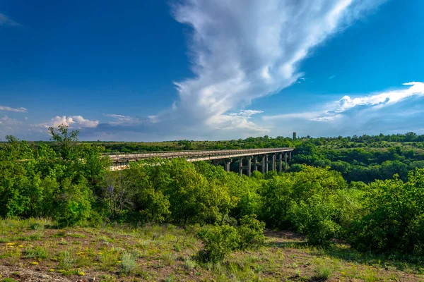 Ancient old bridge over Southern Bug. Yuzhny Buh river flow through green trees. Nature landscape
