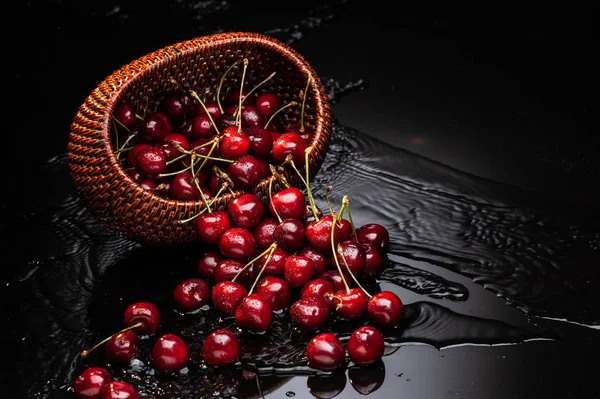 Cereja madura dispersa e cesta de vime — Fotografia de Stock