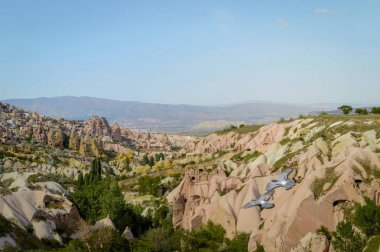 aerial view of mountains and cityscape under bright blue sky in Cappadocia, Turkey  clipart