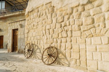 front view of wooden wheels and stone building in Cappadocia, Turkey  clipart