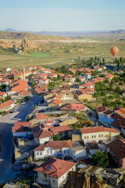 aerial view of hot air balloon flying over buildings in city, Cappadocia, Turkey clipart