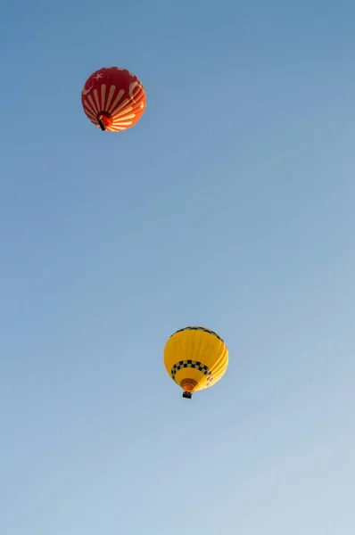 Globos de aire caliente amarillos y rojos volando en cielo azul sin nubes, Capadocia, Turquía - foto de stock