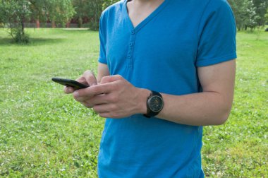Cep telefonuna mesaj yazan saatli adam. Akıllı telefon kullanan genç