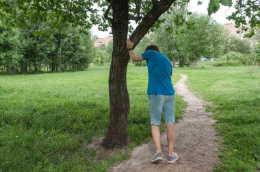 Ağacın yanında koştuktan sonra yorgun bir adam. Dinlenme sporcusu