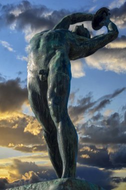 Atina, Yunanistan. Konstantinos Dimitriadis tarafından yapılan Discus Thrower heykeli. Panathenaic Stadyumu'nun karşısında yer alan stadyum 2 metre yüksekliğe ulaşır. Renkli bulutlu gökyüzü ile gün batımı zamanı