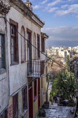 Plaka, Atina / Yunanistan. Atina'nın merkezini gören, Akropolis'in altındaki Plaka'nın tarihi bölgesinde dar bir sokakta, eski geleneksel terk edilmiş ev. Güneşli gün, bulutlu gökyüzü