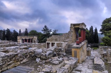 Knossos Palace, Girit / Yunanistan. Knossos arkeolojik sitesinde şarj boğa fresk ile Kuzey Girişi restore. Arka planda Kuzey Lustral Havzası oda. Gün batımı, bulutlu gökyüzü