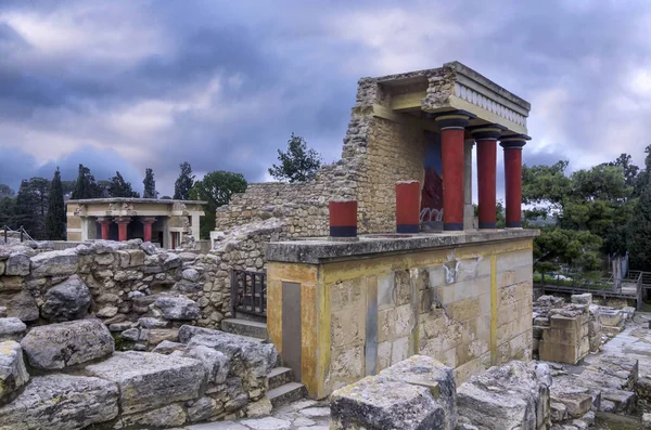 Knossos Palace, Girit / Yunanistan. Knossos arkeolojik sitesinde şarj boğa fresk ile Kuzey Girişi restore. Arka planda Kuzey Lustral Havzası oda. Gün batımı, bulutlu gökyüzü