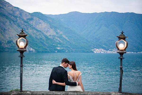 Matrimonio coppia baci sullo sfondo di un lago e montagne — Foto Stock