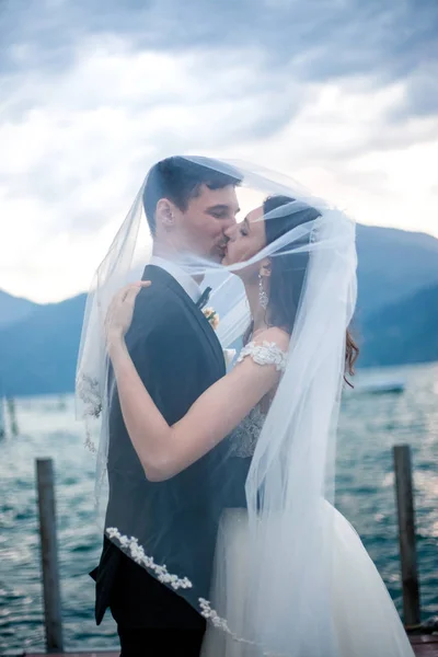Casamento casal beijando no fundo de um lago e montanhas — Fotografia de Stock