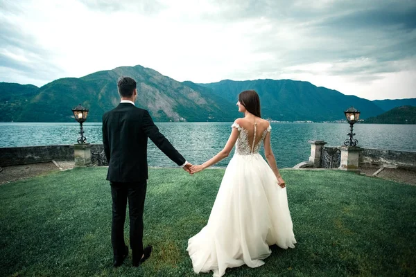 Casamento Casal Correndo Longo Grama Contra Fundo Lago Montanhas — Fotografia de Stock