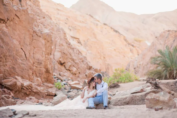 一对美丽的新婚夫妇在峡谷中亲吻棕榈树的背景 — 图库照片