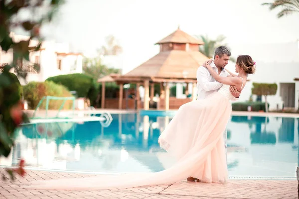 Yeni evli çift düğün lüks tatil sonra. Romantik gelin ve damat yüzme havuzu rahatlatıcı. Balayı. Tropik ülke.
