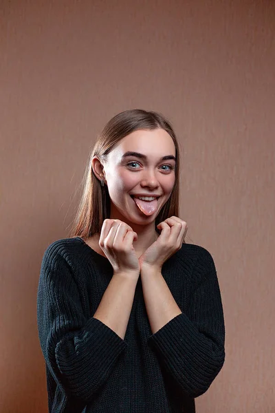 A menina ri e cobre o rosto com as mãos em uma camisola preta — Fotografia de Stock