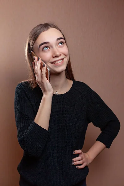 Sarı bir arka plan telefonda konuşurken güzel genç kadın — Stok fotoğraf