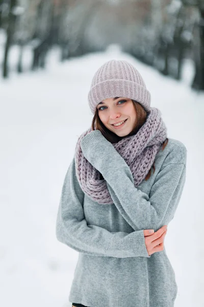 Красива усміхнена дівчина стоїть на дорозі в капелюсі і светрі взимку — стокове фото