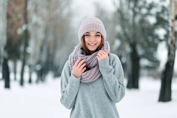 Beautiful smiling girl stands on the road in a hat and sweater in the winter — Stock Photo, Image