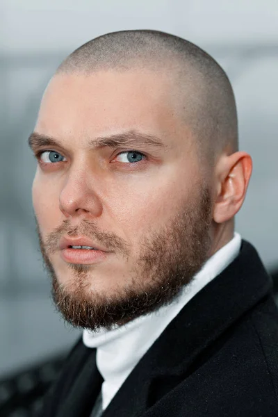 short-haired young man in a black coat looks into the distance on the embankment against the background of the bridge. fog