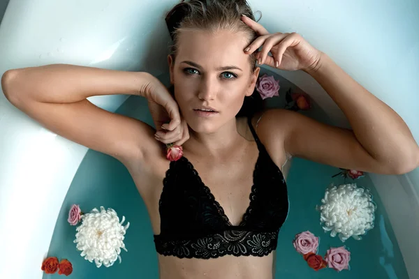 Vacker ung flicka i badrummet med vatten och rose i svart underkläder — Stockfoto