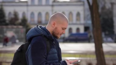 Genç kel adam turistik kentin içinde yürür