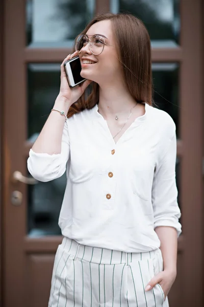 Bela jovem mulher em uma blusa com um telefone — Fotografia de Stock