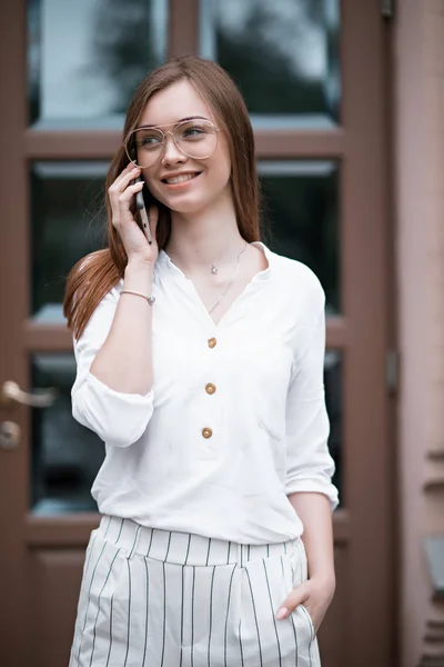 Bela jovem mulher em uma blusa com um telefone — Fotografia de Stock