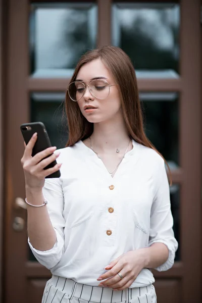 Hermosa joven en una blusa con un teléfono —  Fotos de Stock